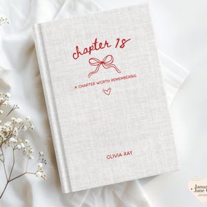 May include: A hardcover book with a light beige textured cover. The title "chapter 18" is written in red script, along with "A chapter worth remembering" and "Olivia Ray". A red bow and heart are also featured.