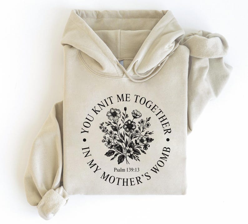 May include: A beige hoodie with a black floral design and the text "You knit me together in my mother's womb. Psalm 139:13"
