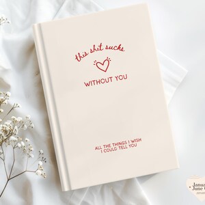 May include: A cream-coloured journal featuring the text "this shit sucks without you" in red script, and a heart graphic. The bottom of the journal reads "all the things I wish I could tell you."
