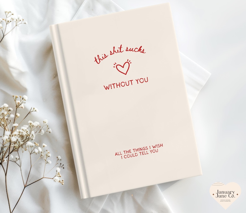 May include: A cream-coloured journal featuring the text "this shit sucks without you" in red script, and a heart graphic. The bottom of the journal reads "all the things I wish I could tell you."