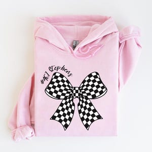 May include: Pink hoodie with a black and white checkered bow and the text "Stephens #467" printed on the front.