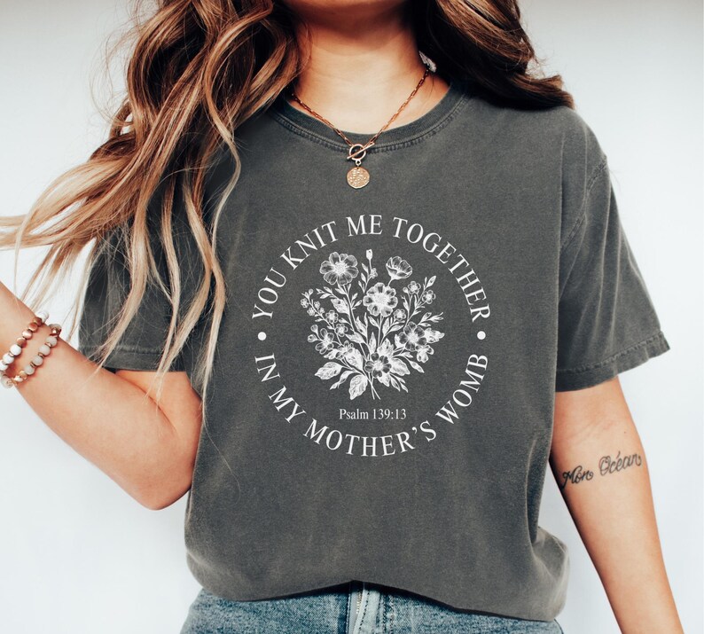 May include: A gray t-shirt with a white graphic that says "You knit me together in my mother's womb" with a floral design and the text "Psalm 139:13".