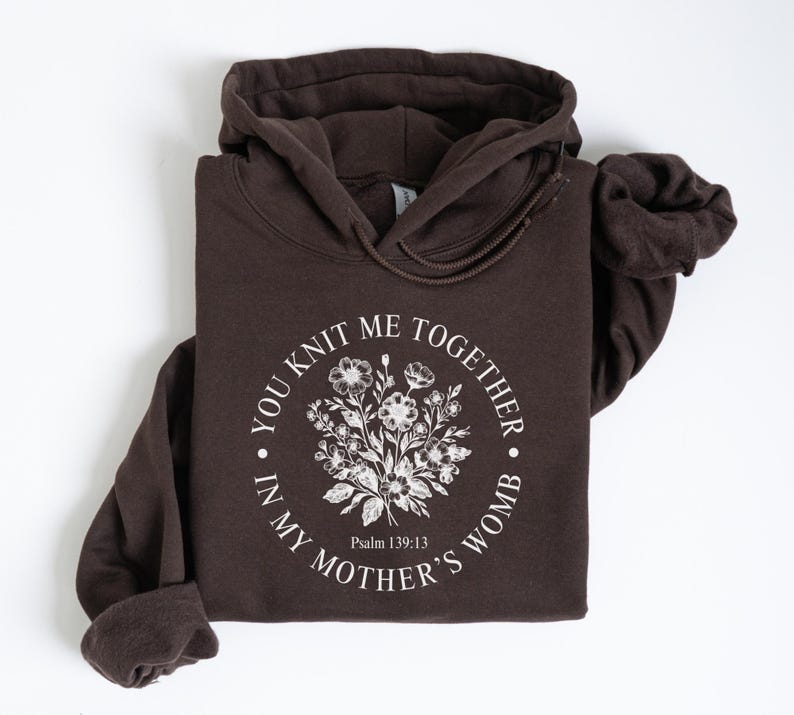 May include: A brown hoodie with a white floral design and the text "You knit me together in my mother's womb" with the scripture reference "Psalm 139:13".