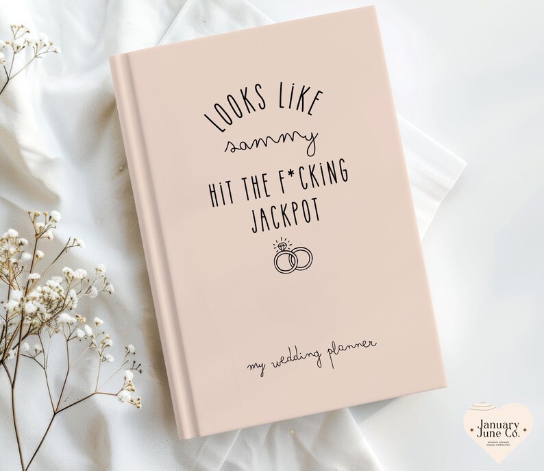 K&ouml;nnte beinhalten: Ein rosafarbenes Hochzeitsplaner-Buch mit schwarzem Text "LOOKS LIKE sammy HIT THE F*CKING JACKPOT". Es enth&auml;lt eine Ringgrafik und die Worte "my wedding planner".