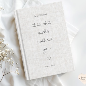 Peut inclure: Un journal &agrave; couverture rigide avec une couverture textur&eacute;e blanc cass&eacute;. La couverture pr&eacute;sente le texte "Dear Michael, this shit sucks without you" dans une police manuscrite, suivi d'un symbole de c&oelig;ur et "Love, Amy."