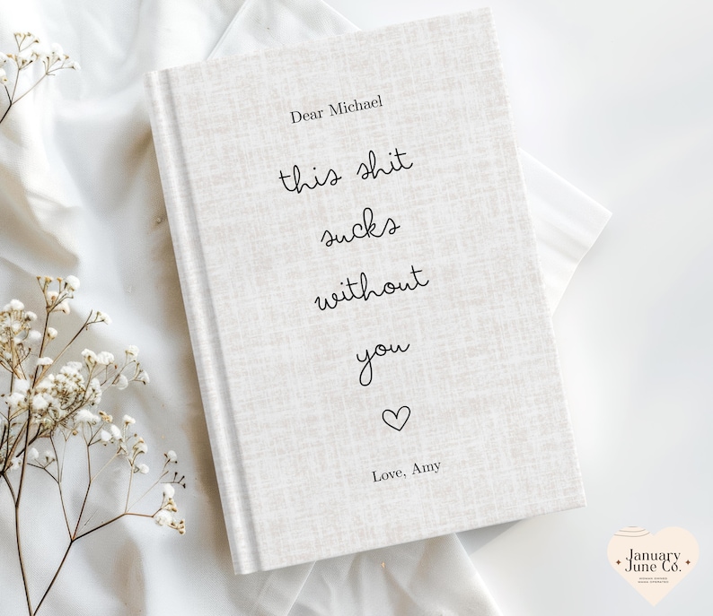 Peut inclure: Un journal &agrave; couverture rigide avec une couverture textur&eacute;e blanc cass&eacute;. La couverture pr&eacute;sente le texte "Dear Michael, this shit sucks without you" dans une police manuscrite, suivi d'un symbole de c&oelig;ur et "Love, Amy."