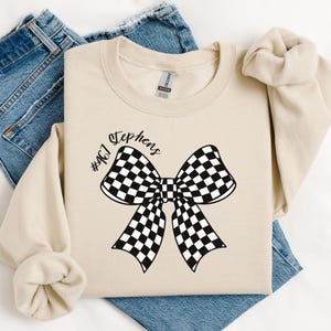 May include: A beige sweatshirt with a black and white checkered bow and the text "#467 Stephens" printed on the front.