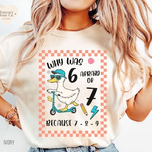 May include: Ivory-colored t-shirt featuring a cartoon duck wearing sunglasses and a cap, riding a scooter. The shirt has the text "WHY WAS 6 AFRAID OF 7 BECAUSE 7-8-9" in a pink and white checkered frame. The brand logo is in the upper left corner.
