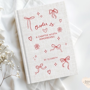 May include: A hardcover book with a light beige linen cover. Red line art includes bows, hearts, flowers, and stars. The text reads "Chapter 25, A Chapter Worth Remembering, By: Elisabeth."
