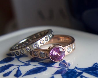May include: Two rings with a pink gemstone and small diamonds. The top ring is rose gold with a pink gemstone and small diamonds. The bottom ring is silver with small diamonds.