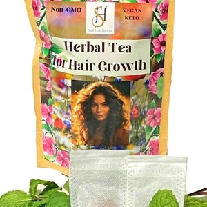 May include: A brown paper bag with a white label that says "Herbal Tea for Hair Growth". The label also says "Non-GMO", "Vegan Keto", and "Svetla-Herbs". The bag contains two white tea bags. The tea bags are surrounded by green mint leaves.