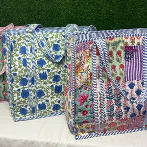 May include: Three tote bags made of patchwork fabric with floral patterns. The bags have blue, pink, green, and white floral designs. The bags have blue and white striped handles.