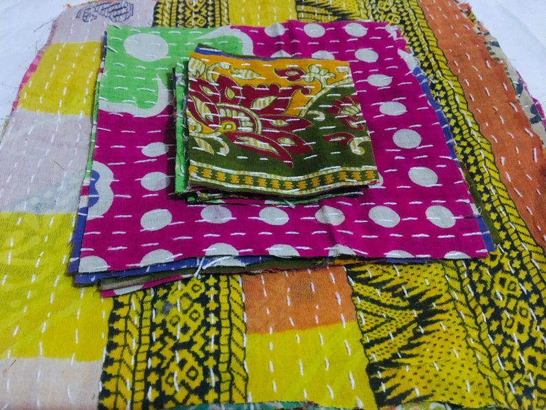 May include: A stack of colorful fabric squares with different patterns, including polka dots, floral designs, and geometric shapes. The fabric is stitched together with white thread.