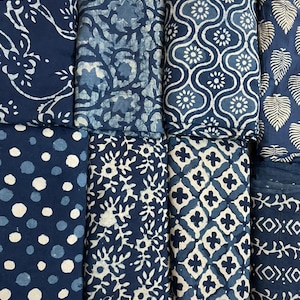 May include: A collection of eight fabric swatches featuring various indigo blue and white patterns. The patterns include floral, geometric, and leaf designs.
