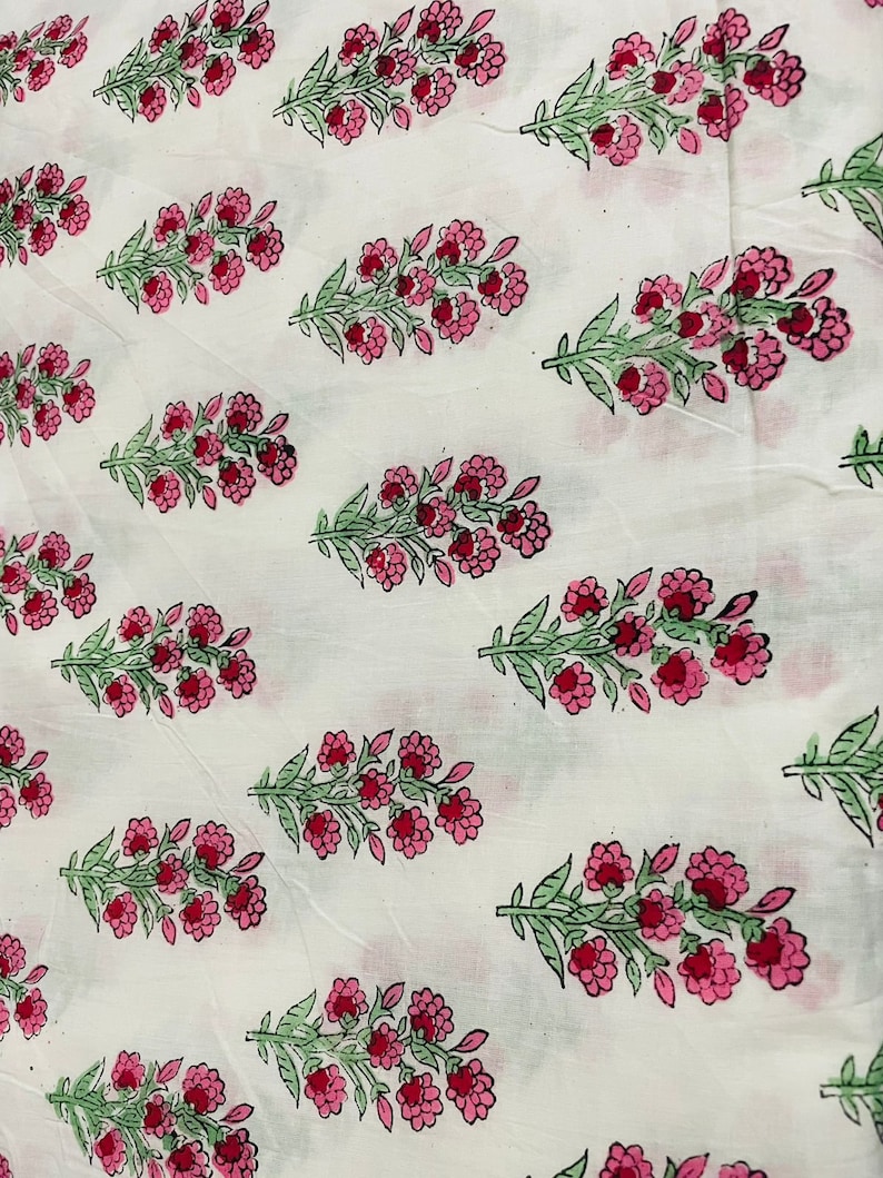 May include: White fabric with a repeating pattern of pink and green floral sprigs. The fabric has a subtle texture.