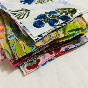 Puede incluir: Una pila de cuadrados de tela coloridos con patrones florales. Los cuadrados son de algod&oacute;n y son perfectos para acolchar, patchwork u otros proyectos de artesan&iacute;a.