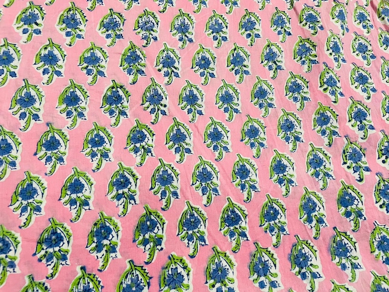 May include: Pink fabric with a repeating pattern of blue and green floral designs.