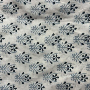 May include: White fabric with a repeating pattern of black and gray stylized flowers and leaves.