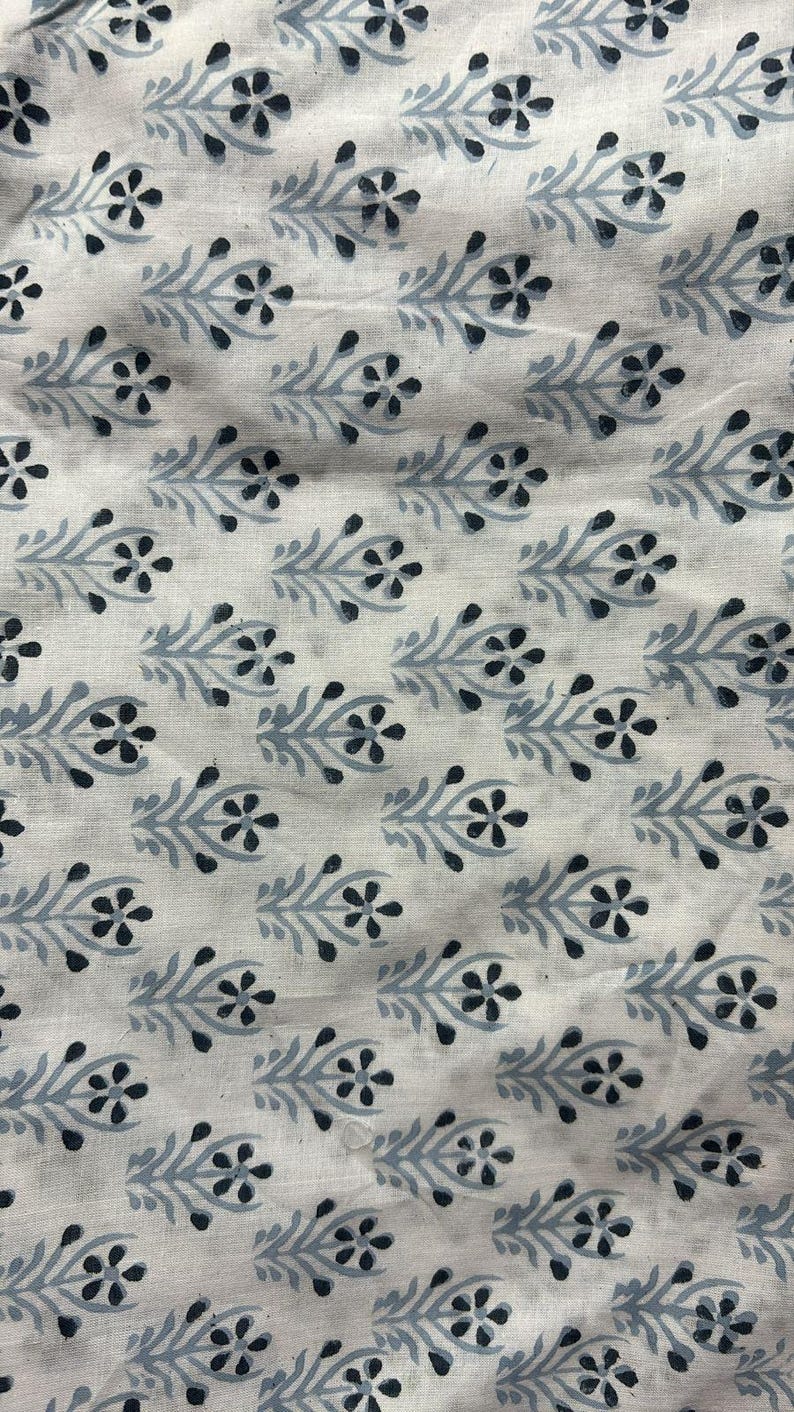 May include: White fabric with a repeating pattern of black and gray stylized flowers and leaves.