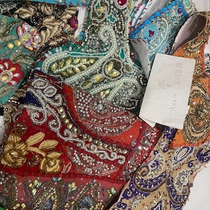 May include: A close-up of colorful fabric scraps with intricate beading and embroidery. The fabrics are in shades of red, blue, green, gold, and purple. The text "BEADED WORK" is written on a white piece of paper.