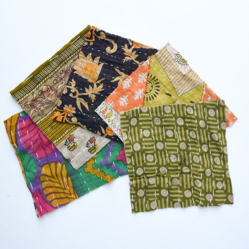 May include: A collection of six fabric squares with different patterns and colors, including green, orange, purple, and black. The fabric squares are made of cotton and have a patchwork design.