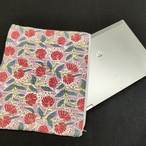 May include: A pink and blue floral laptop sleeve with a zipper closure. The sleeve is made of cotton and has a quilted texture. The sleeve is shown with a silver laptop inside.