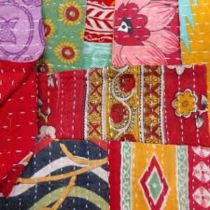 May include: A colorful patchwork quilt made from various fabrics with floral and geometric patterns. The quilt is stitched together with white thread and has a rustic, handmade look.