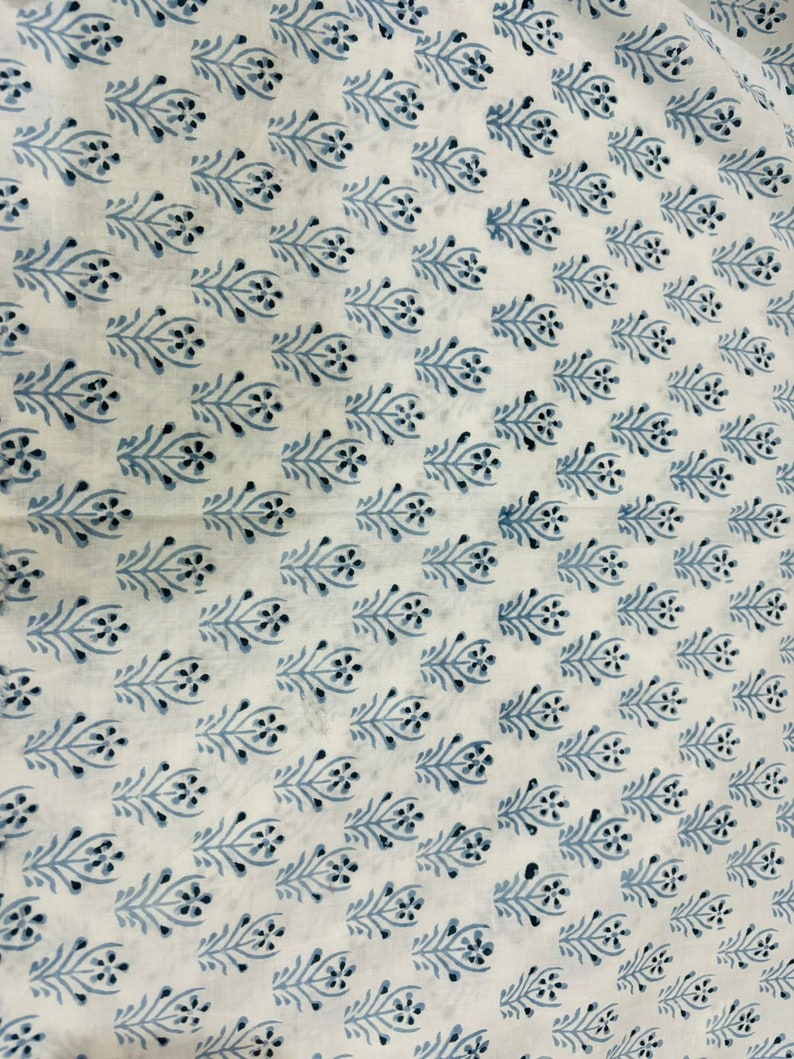 May include: White fabric with a repeating pattern of blue floral sprigs. The sprigs are stylized and have a simple, elegant design.