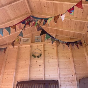 May include: A wooden cabin interior decorated with a colorful fabric bunting and a wooden sign that says "Welcome".