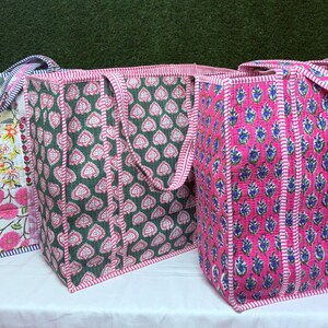 May include: Three tote bags made of quilted fabric with different floral patterns. The bags are pink, green, and blue with white accents. The bags have two handles and are made of a soft, durable fabric.