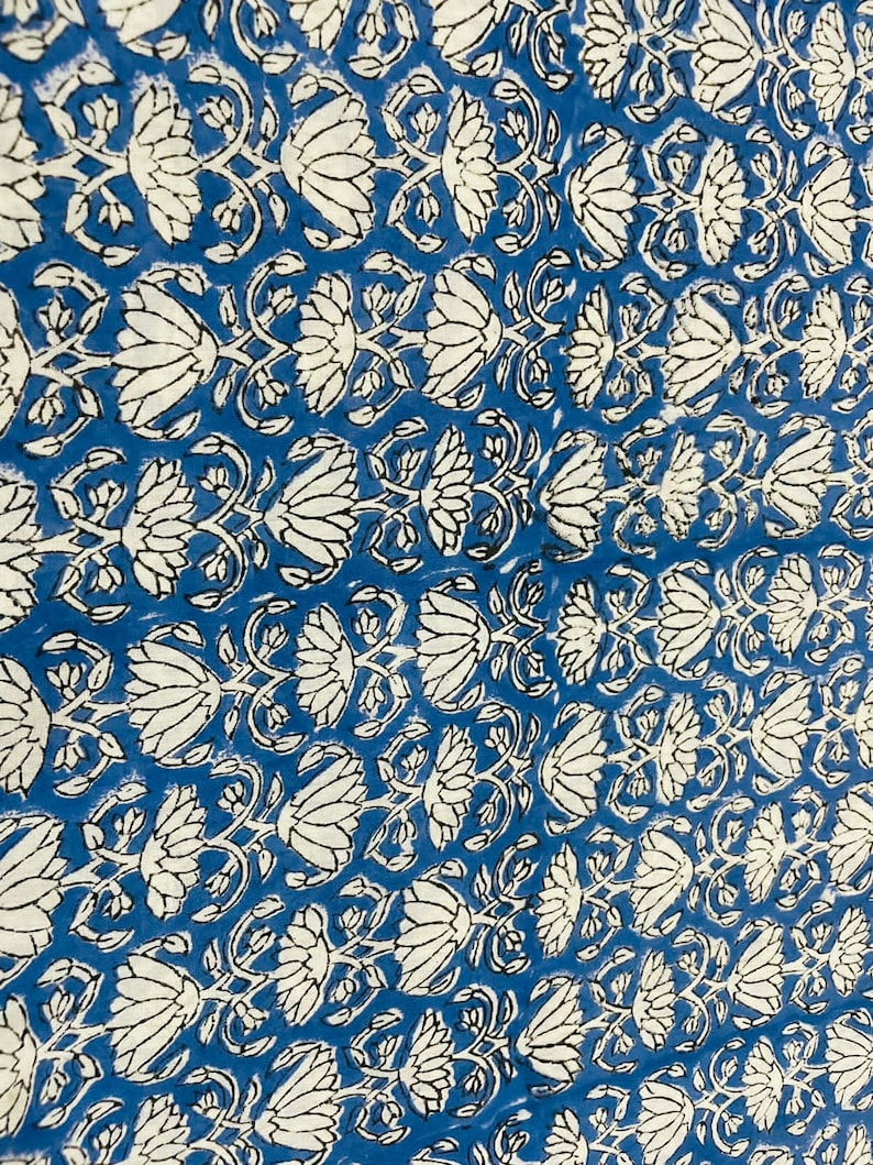 May include: Blue fabric with a white floral pattern. The pattern features stylized lotus flowers with intricate details.