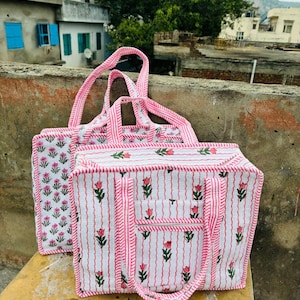 May include: Three pink and white striped tote bags with floral patterns. The bags have pink and white striped handles.