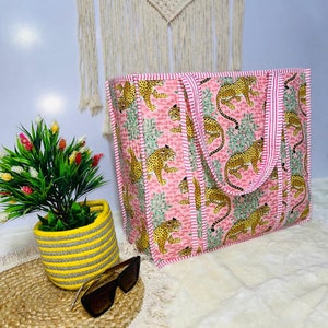Pu&ograve; includere: Una borsa tote rosa e bianca con un motivo a stampa leopardata. La borsa ha due manici ed &egrave; realizzata in tessuto trapuntato.