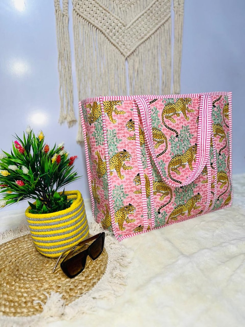 Pu&ograve; includere: Una borsa tote rosa e bianca con un motivo a stampa leopardata. La borsa ha due manici ed &egrave; realizzata in tessuto trapuntato.