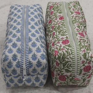 May include: Two rectangular quilted fabric pouches with zippered closures. The left pouch features a blue floral pattern on a white background. The right pouch displays a green and pink floral pattern on a white background with striped zipper tape.