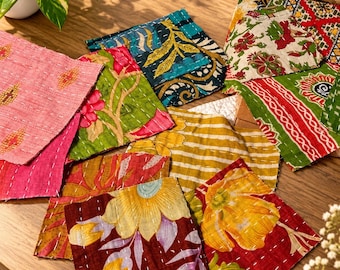 May include: A collection of square fabric patches featuring various floral and geometric patterns in shades of red, yellow, green, blue, and pink. Each piece is stitched with visible white running thread, creating a quilted texture.