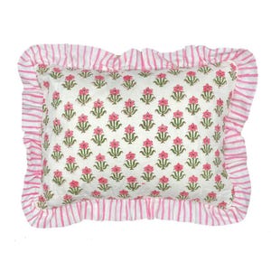 May include: A rectangular throw pillow featuring a white base with a repeating pattern of small pink flowers and green stems. The pillow is framed by a ruffled border with a white and pink vertical stripe pattern, creating a decorative edge.