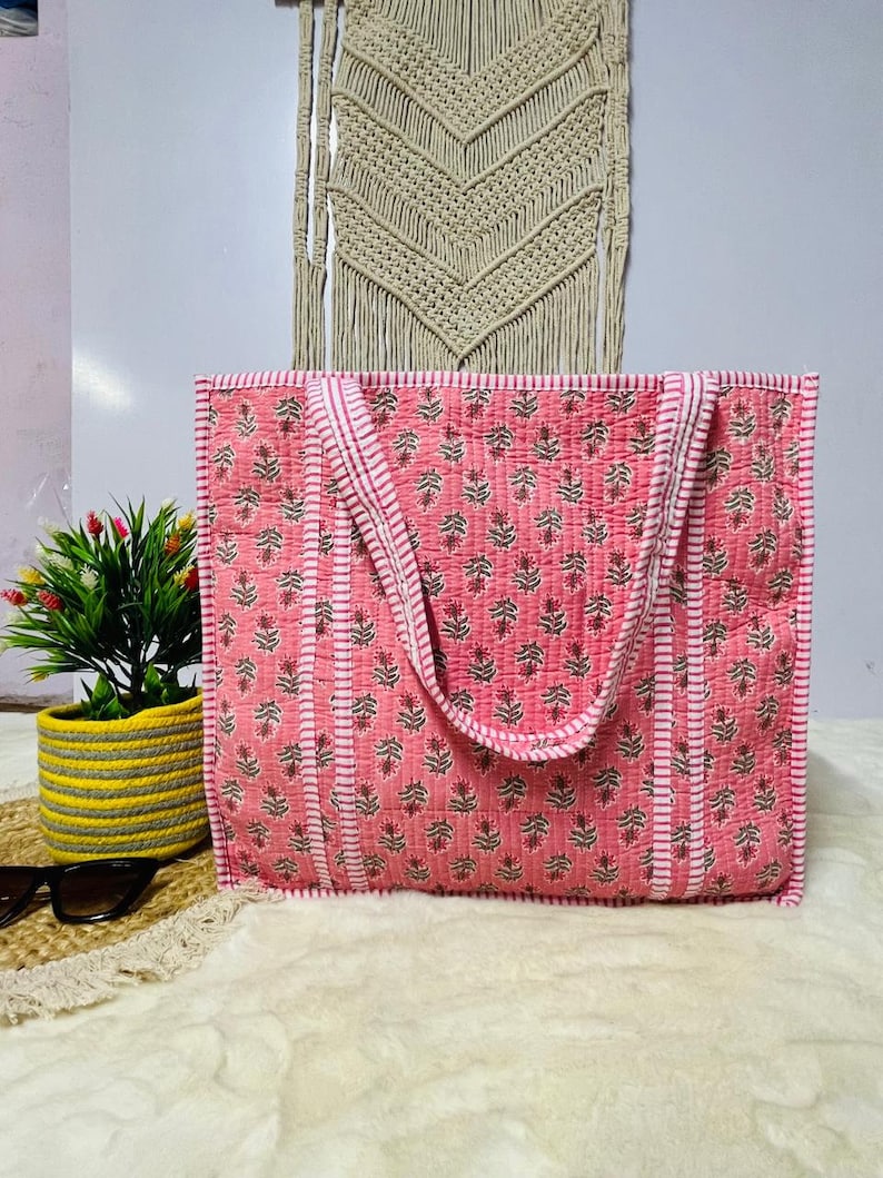 Pu&ograve; includere: Una borsa tote rosa e bianca con stampa floreale. La borsa ha due manici ed &egrave; realizzata in tessuto trapuntato.