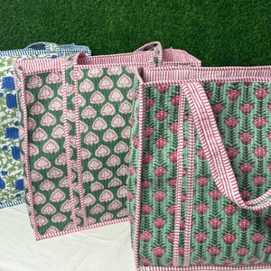 May include: Three tote bags with floral patterns. The bags are made of cotton and have a green, pink, and blue color scheme. The bags have a simple design and are perfect for carrying groceries or other items.