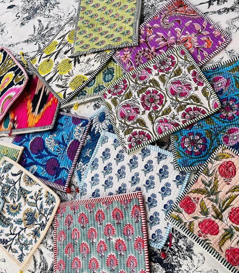 May include: A collection of colorful fabric squares with floral patterns. The squares are quilted and have a white background with various colored floral designs. The squares are arranged in a random pattern and have a black and white trim.