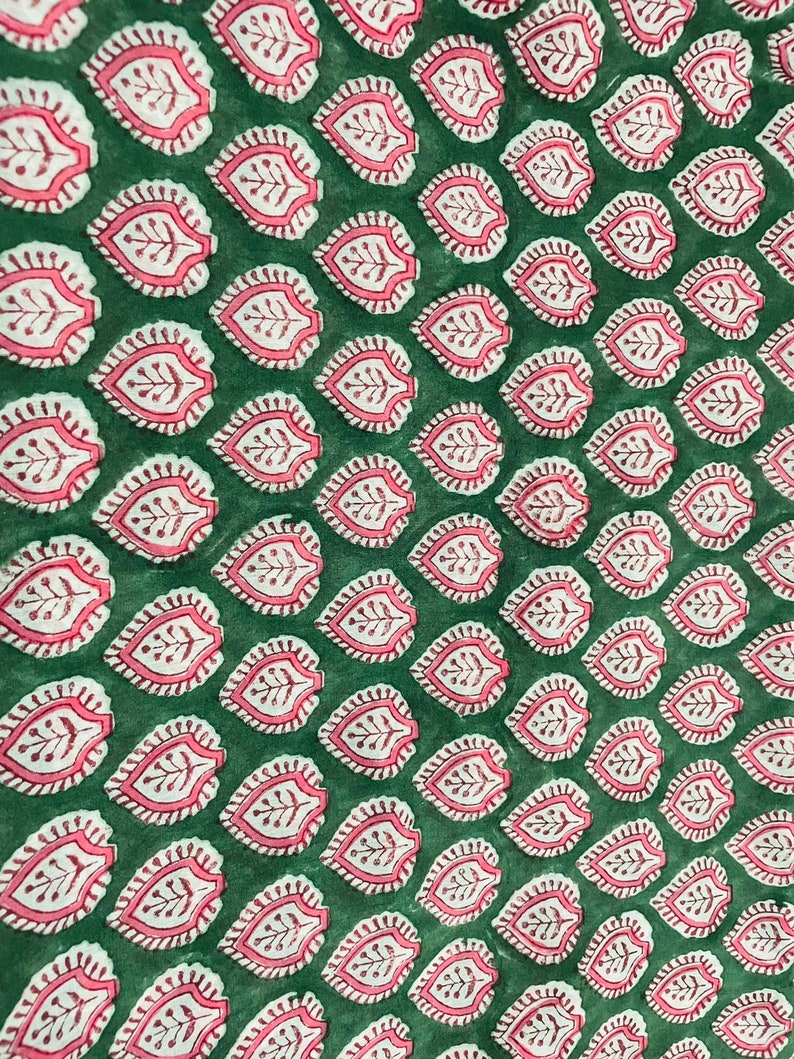 May include: Green fabric with a repeating pattern of pink and white leaf designs.