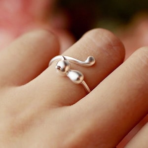 May include: A silver ring with a cat design. The cat's tail wraps around the finger.