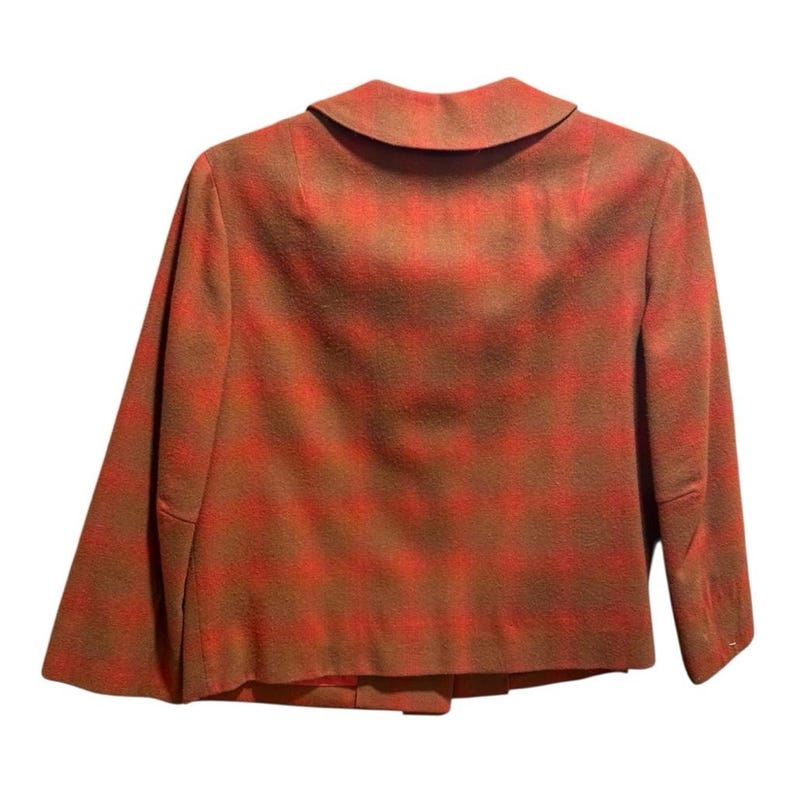 May include: A vintage blazer in a plaid pattern, viewed from the back. The jacket features a brown and red color scheme, with a classic collar and tailored fit. The fabric appears to be a wool blend, suitable for cooler weather.