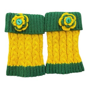 May include: A pair of knitted leg warmers in yellow and green. The leg warmers have a cable knit pattern in yellow with green cuffs and tops. Each leg warmer is adorned with a yellow and green flower with a green button.
