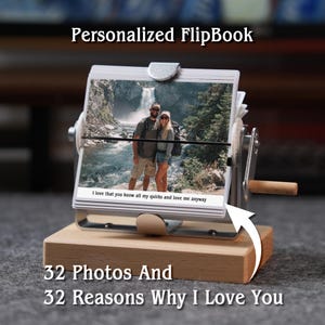 May include: A personalized flipbook with 32 photos and 32 reasons why I love you. The flipbook has a metal frame and a wooden base. The text "I love that you know all my quirks and love me anyway" is visible.