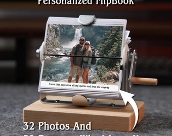 May include: A personalized flipbook with 32 photos and 32 reasons why I love you. The flipbook has a metal frame and a wooden base. The text "I love that you know all my quirks and love me anyway" is visible.