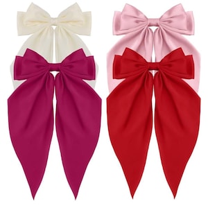 May include: Three large satin hair bows in different colours. The bows are tied in a knot and have long tails. The colours are white, pink, and red.