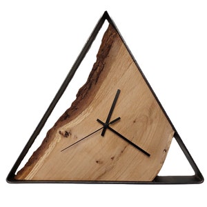 Könnte beinhalten: Eine Holzuhr mit einem dreieckigen Metallrahmen. Das Zifferblatt der Uhr ist aus einer natürlichen Holzscheibe mit einem einzigartigen Maserungsmuster gefertigt. Die Zeiger der Uhr sind schwarz.