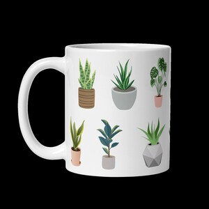 May include: White ceramic mug featuring a repeating pattern of various potted plants in shades of green, brown, and gray. The plants include snake plants, aloe vera, and a monstera. The mug has a curved handle.