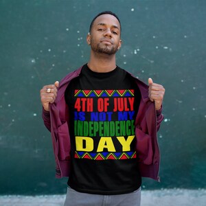 May include: A black t-shirt with a colorful graphic that reads "4th of July is not my Independence Day". The graphic features a red, yellow, green, and blue color scheme with a geometric pattern.